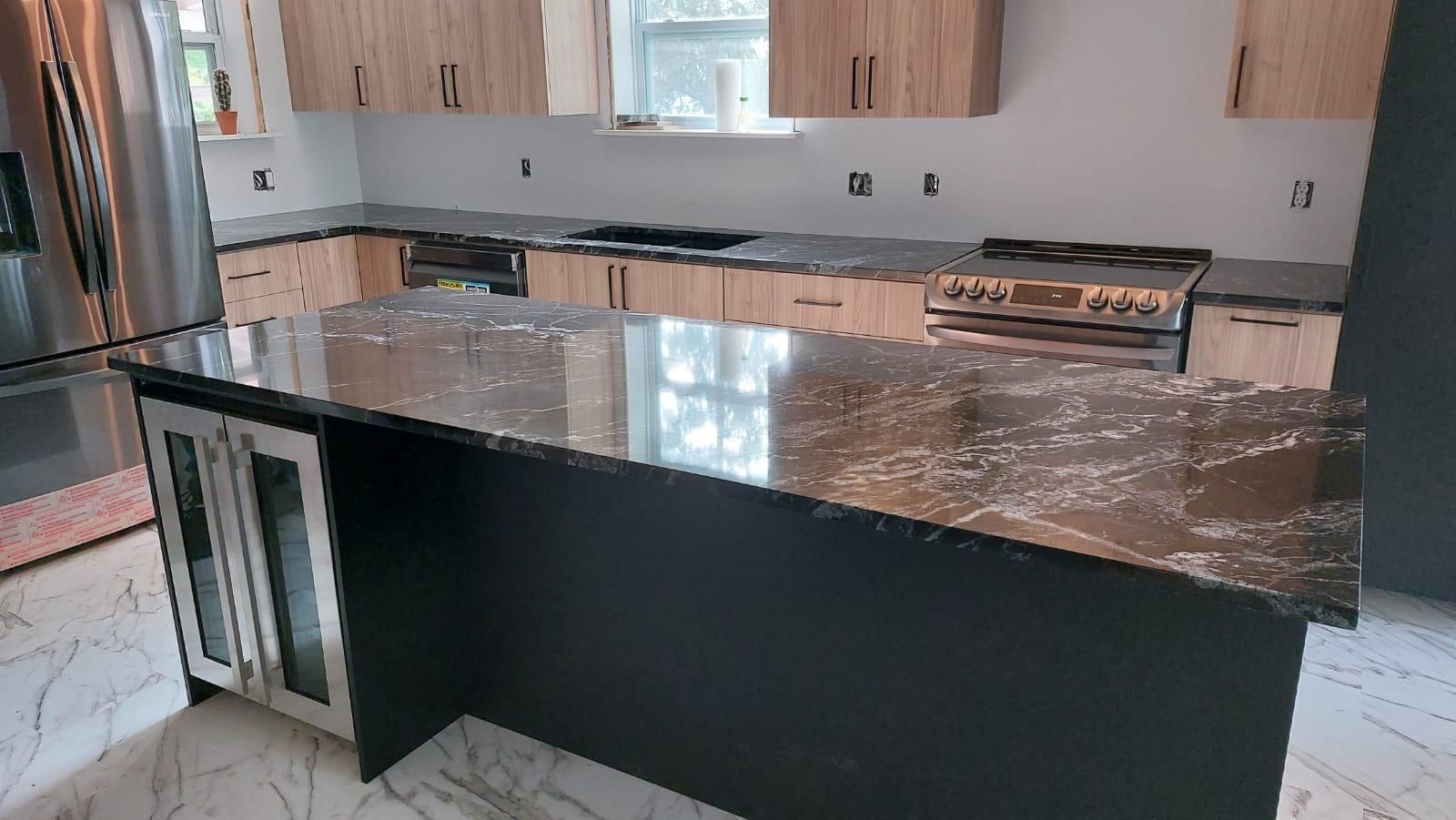 Une cuisine avec comptoirs en granit, appareils électroménagers en acier inoxydable et armoires en bois.