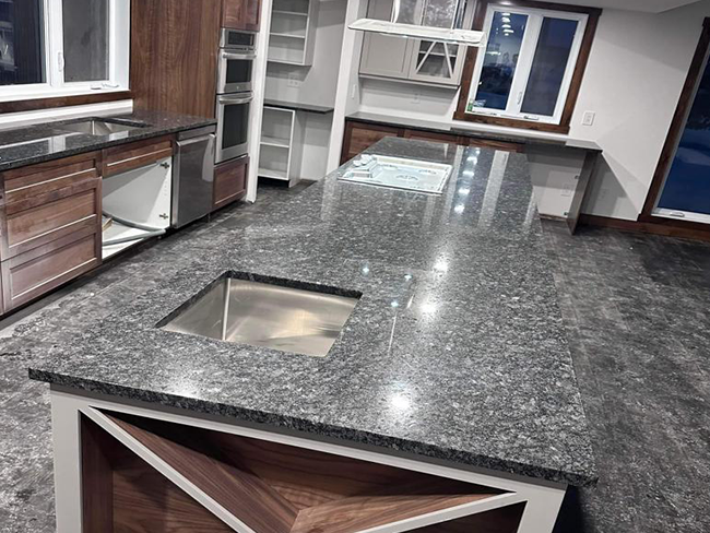 Une cuisine avec comptoirs en granit et un évier en acier inoxydable.