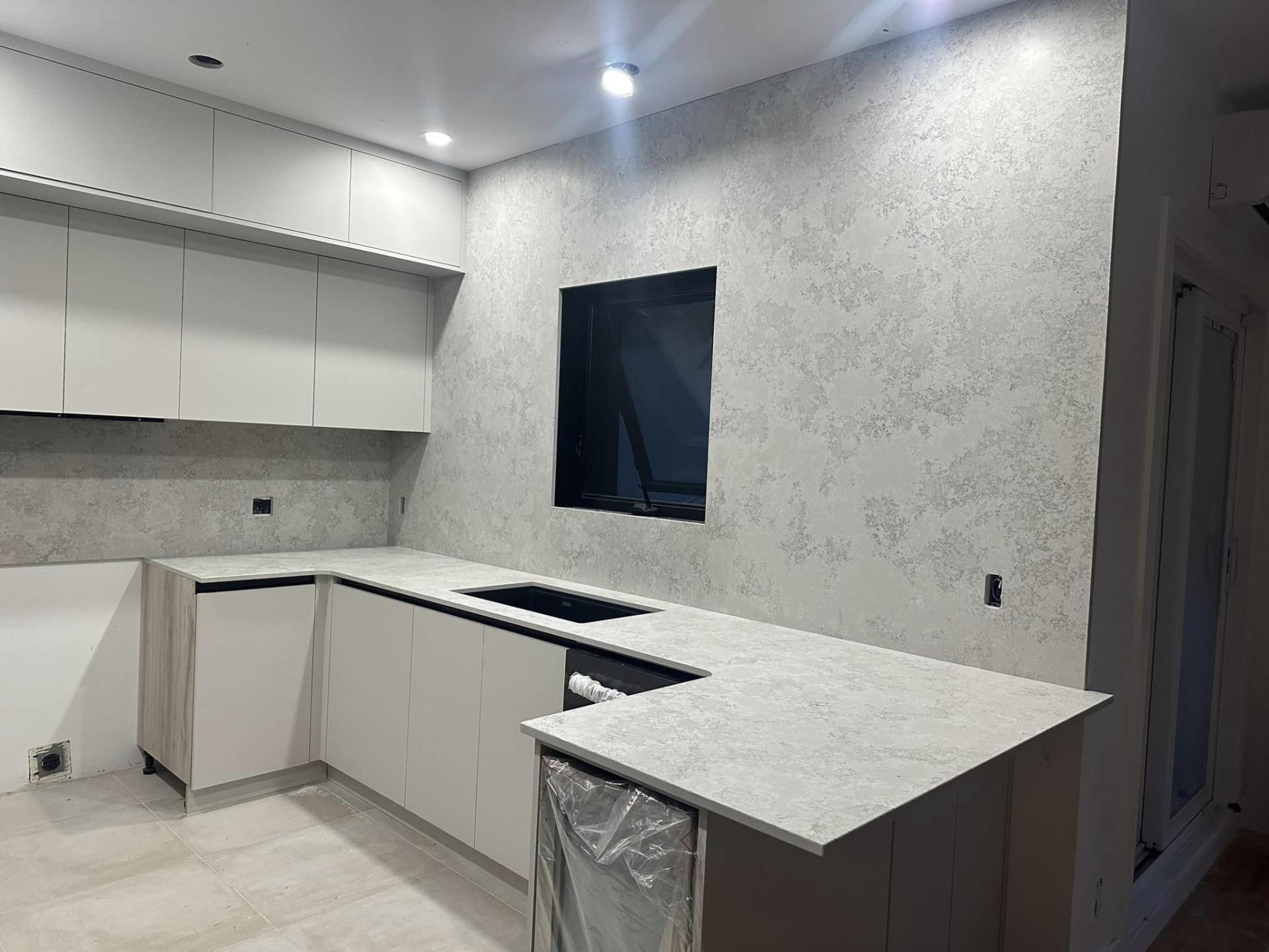 Une cuisine avec des armoires blanches, des comptoirs en granit et un évier.