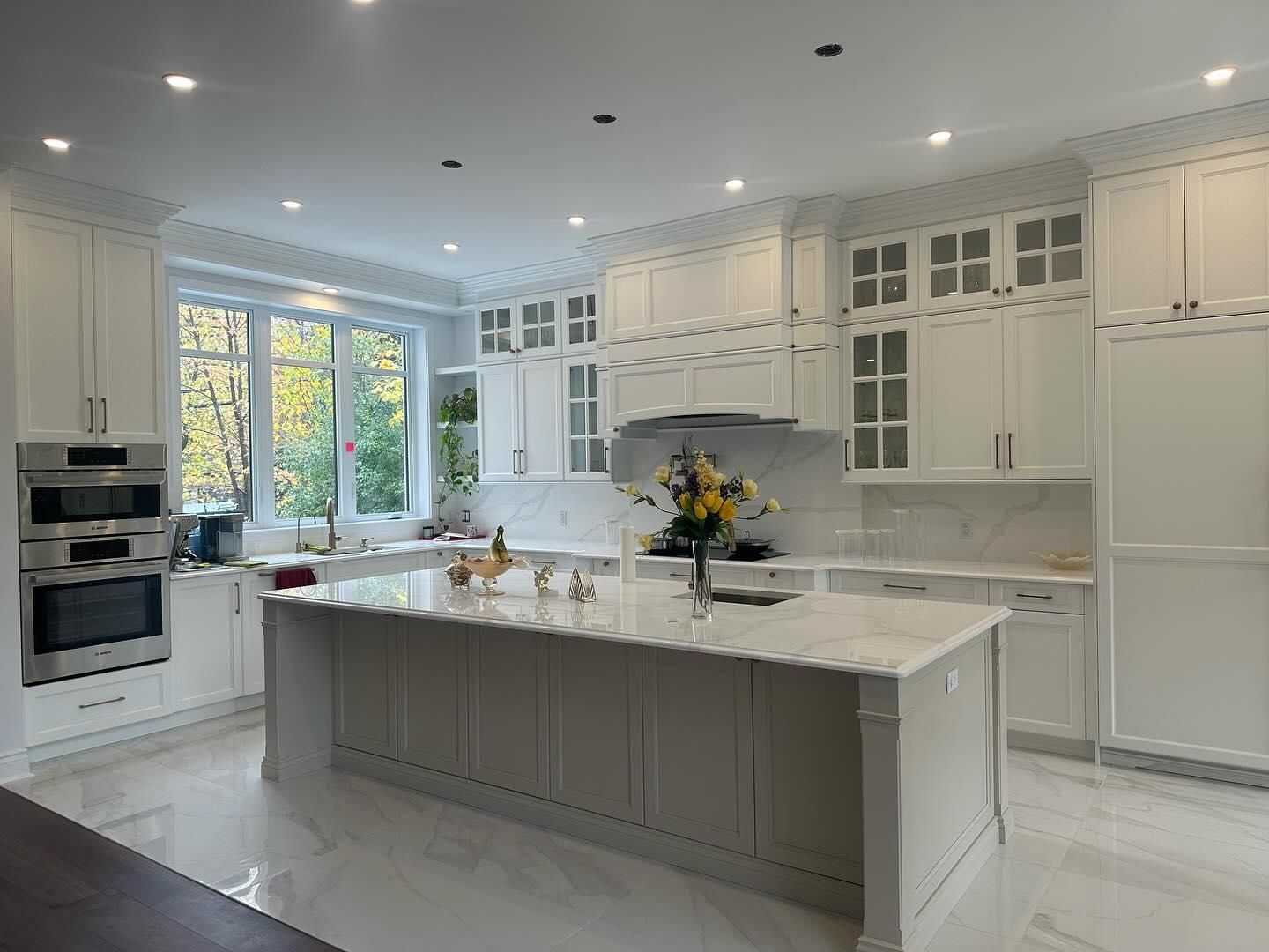 Une cuisine avec des armoires blanches, des comptoirs en granit, des appareils électroménagers en acier inoxydable et un grand îlot.