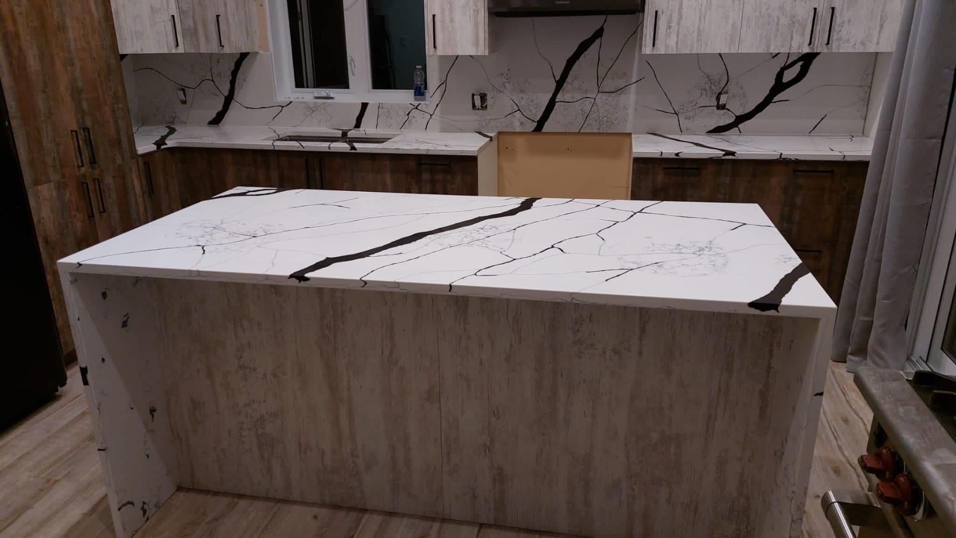 Une cuisine avec un grand îlot et des comptoirs en marbre.