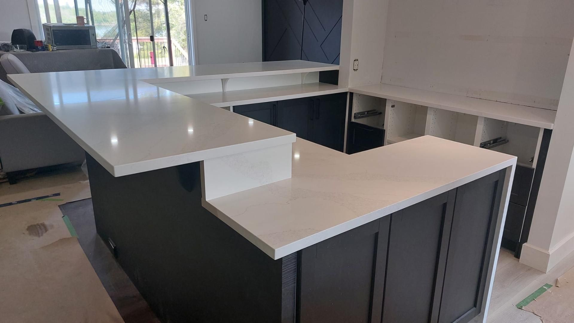 Une cuisine avec un grand îlot et des comptoirs blancs.