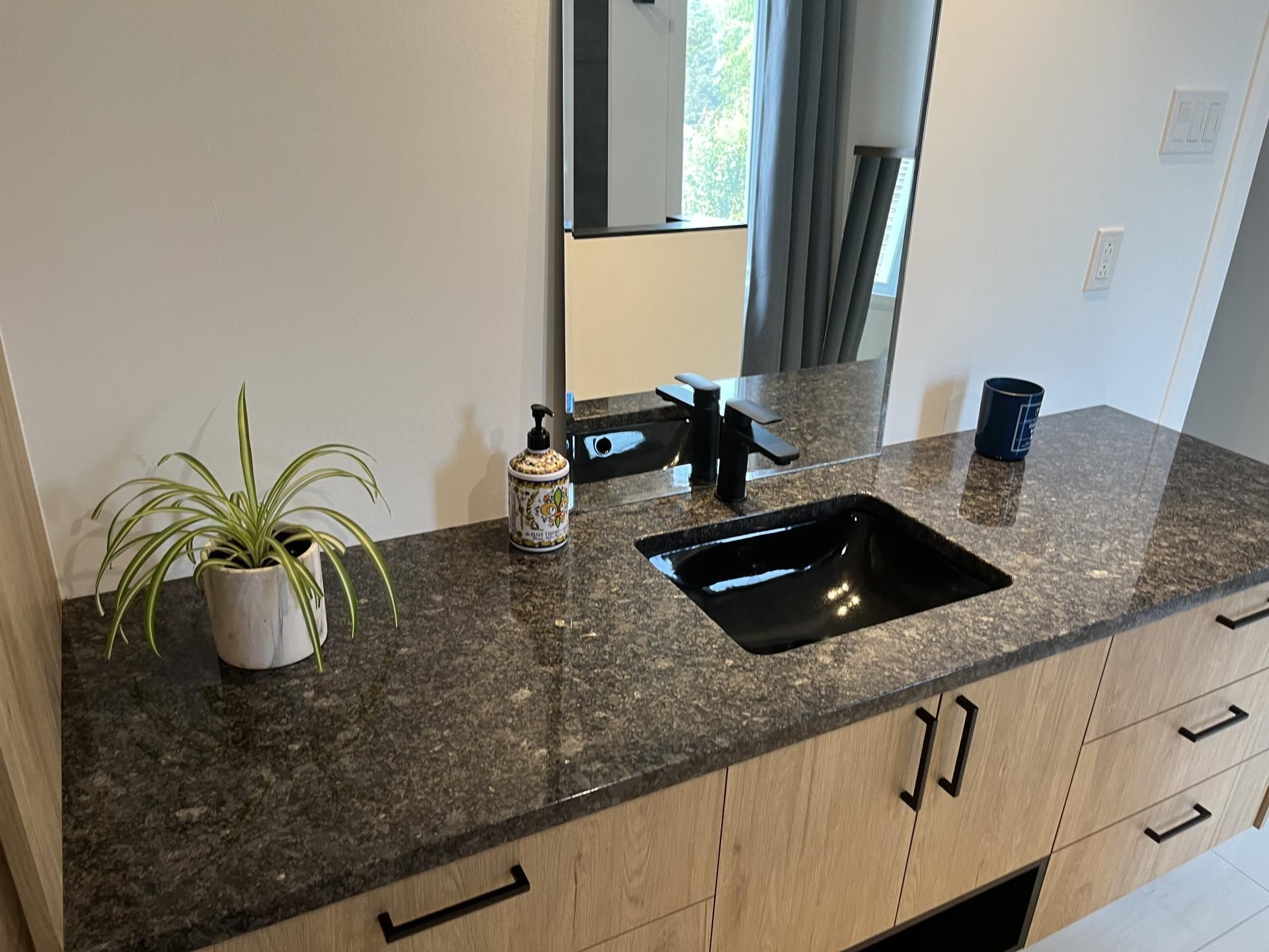 Une vanité de salle de bain avec un lavabo noir et un miroir.