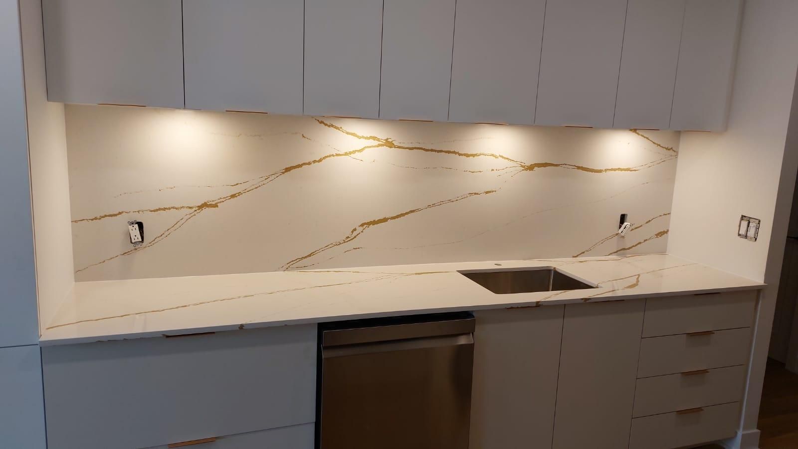 Une cuisine avec des armoires blanches, un évier et un lave-vaisselle.