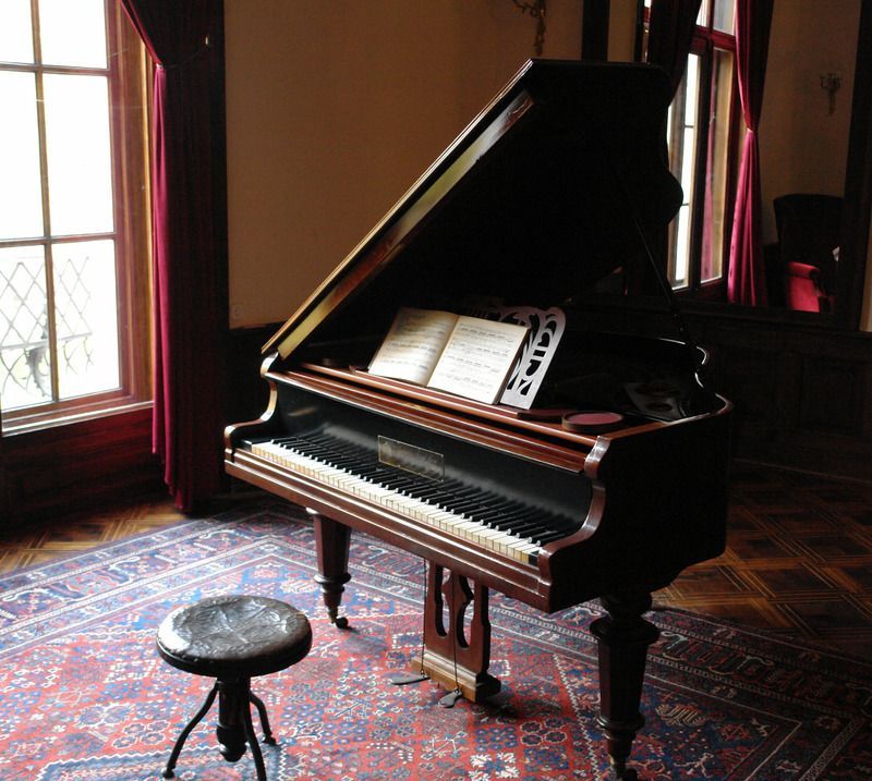 A piano sits in a room next to a window