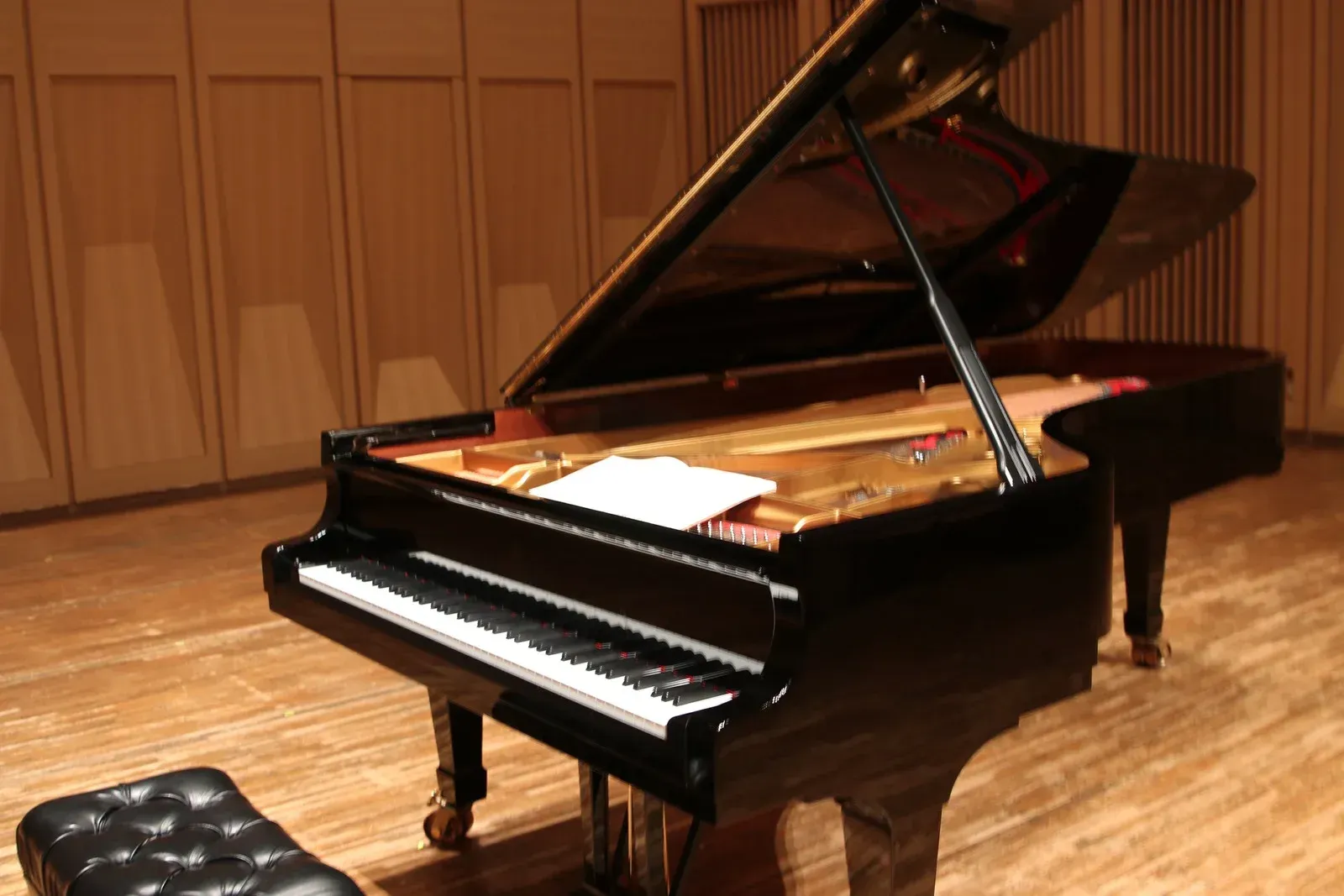 A grand piano is sitting on a wooden floor in a room.