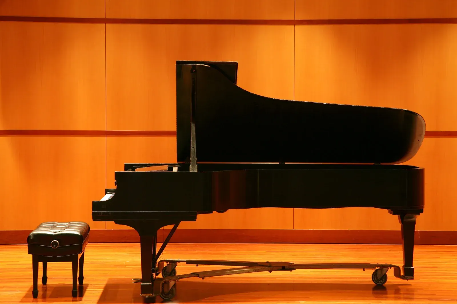 A piano is sitting on a stage next to a bench