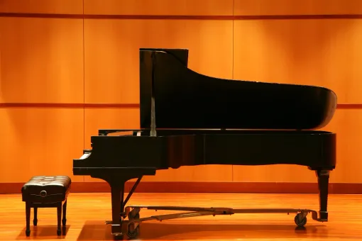 A piano is sitting on a stage next to a bench
