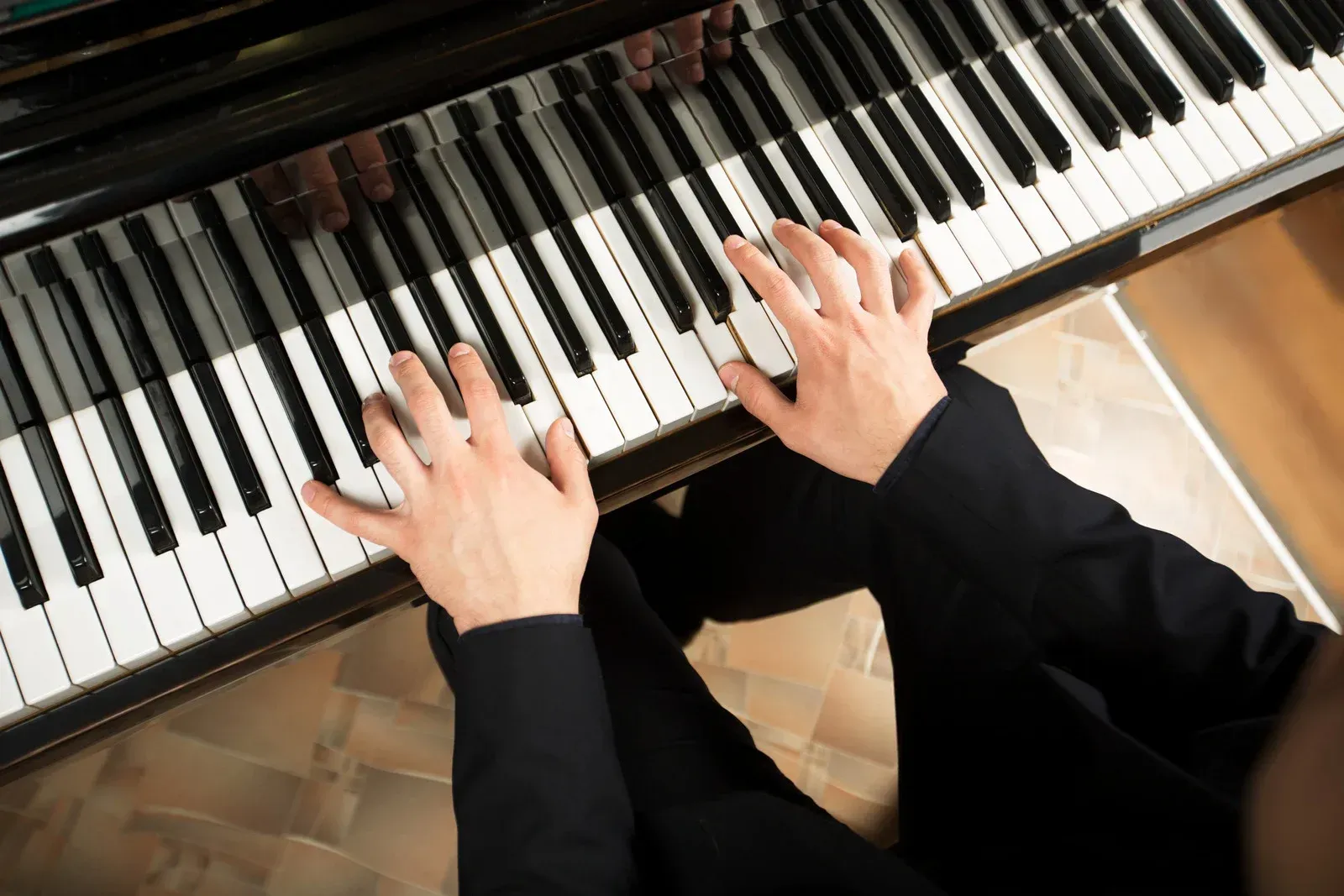 A person is playing a piano with their hands on the keys.