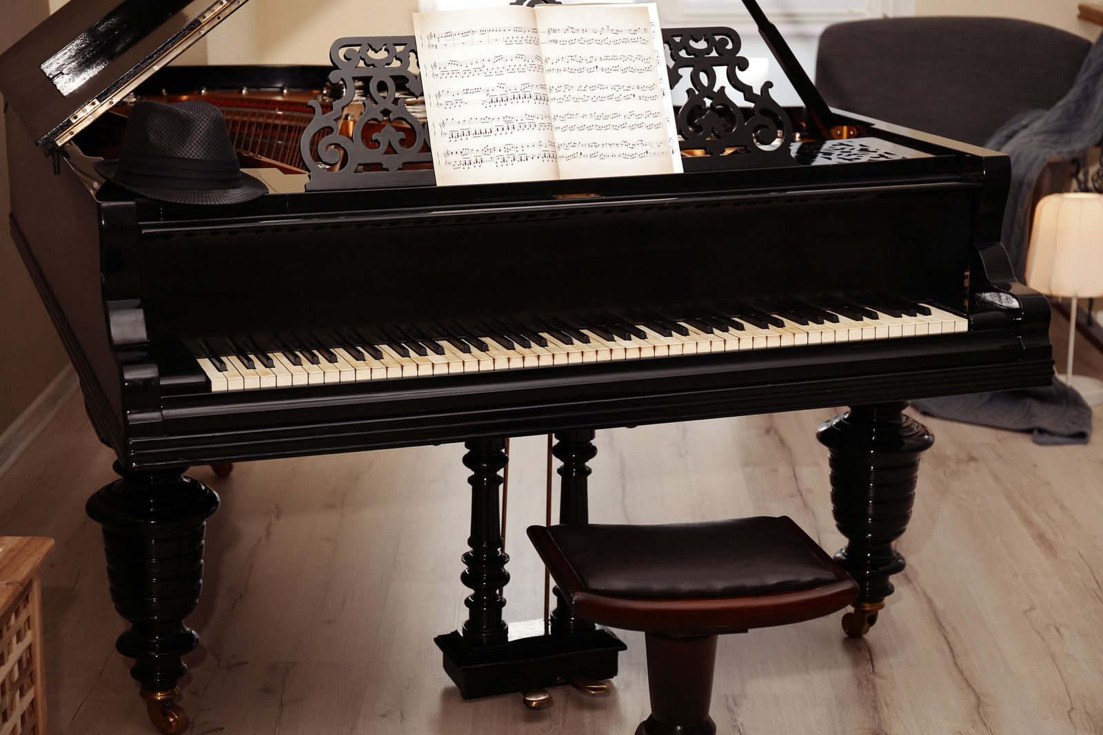 A black grand piano is sitting on a wooden floor in a living room.