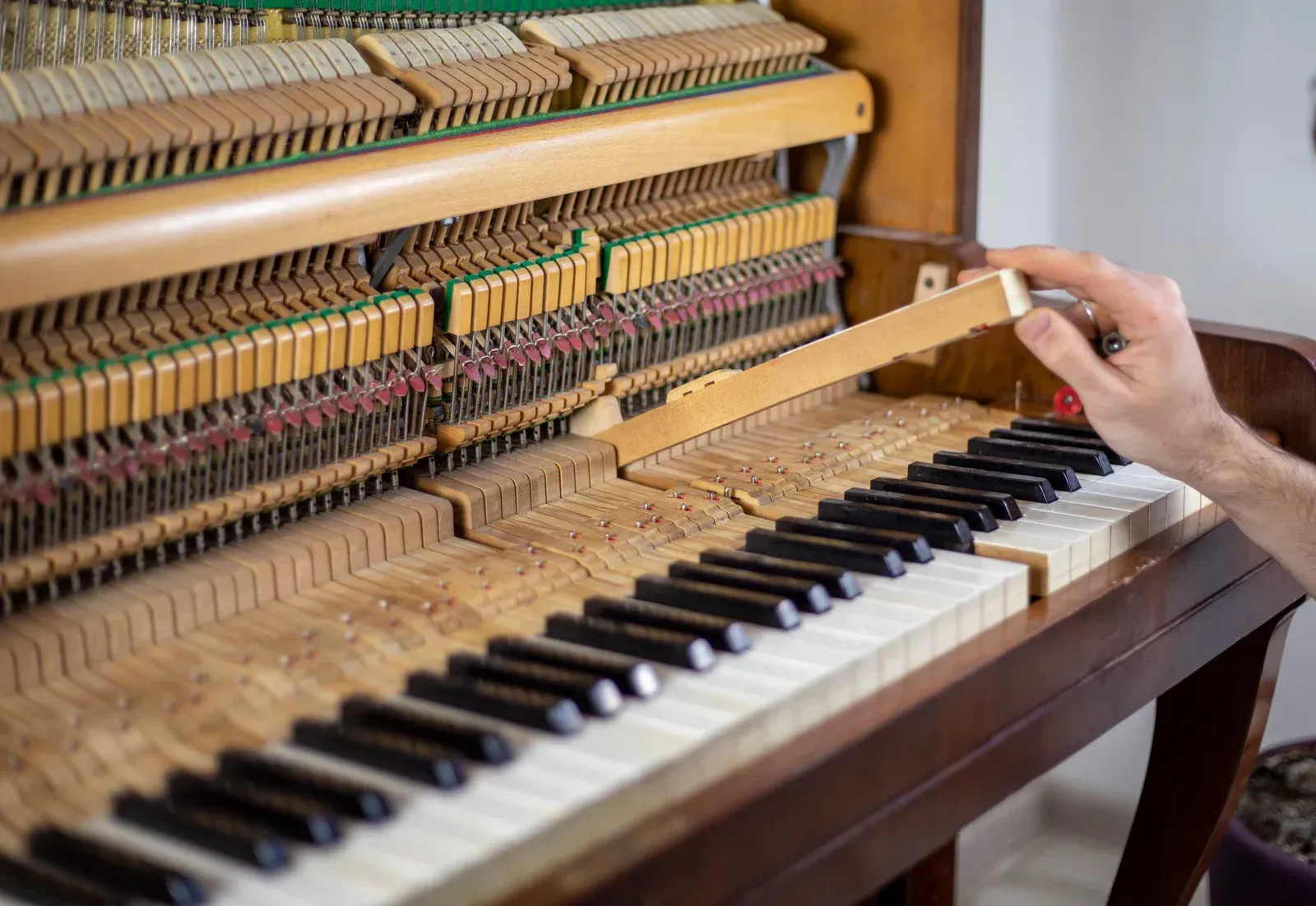 A person is working on a piano with a screwdriver.
