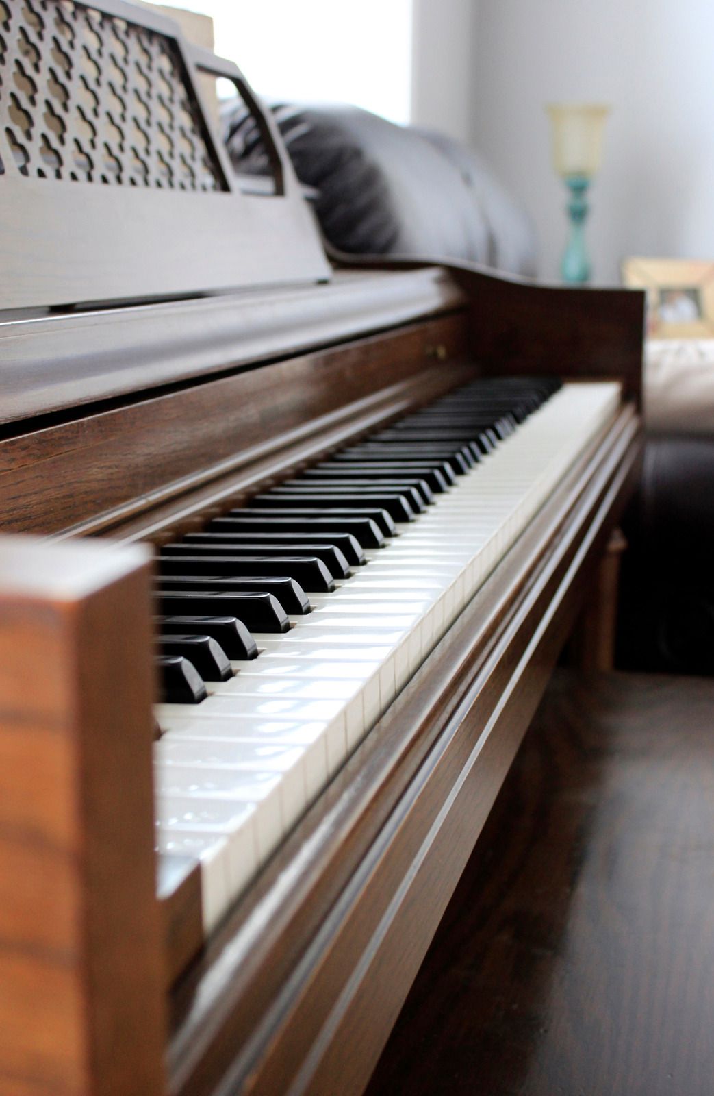 A piano is sitting in a living room next to a couch