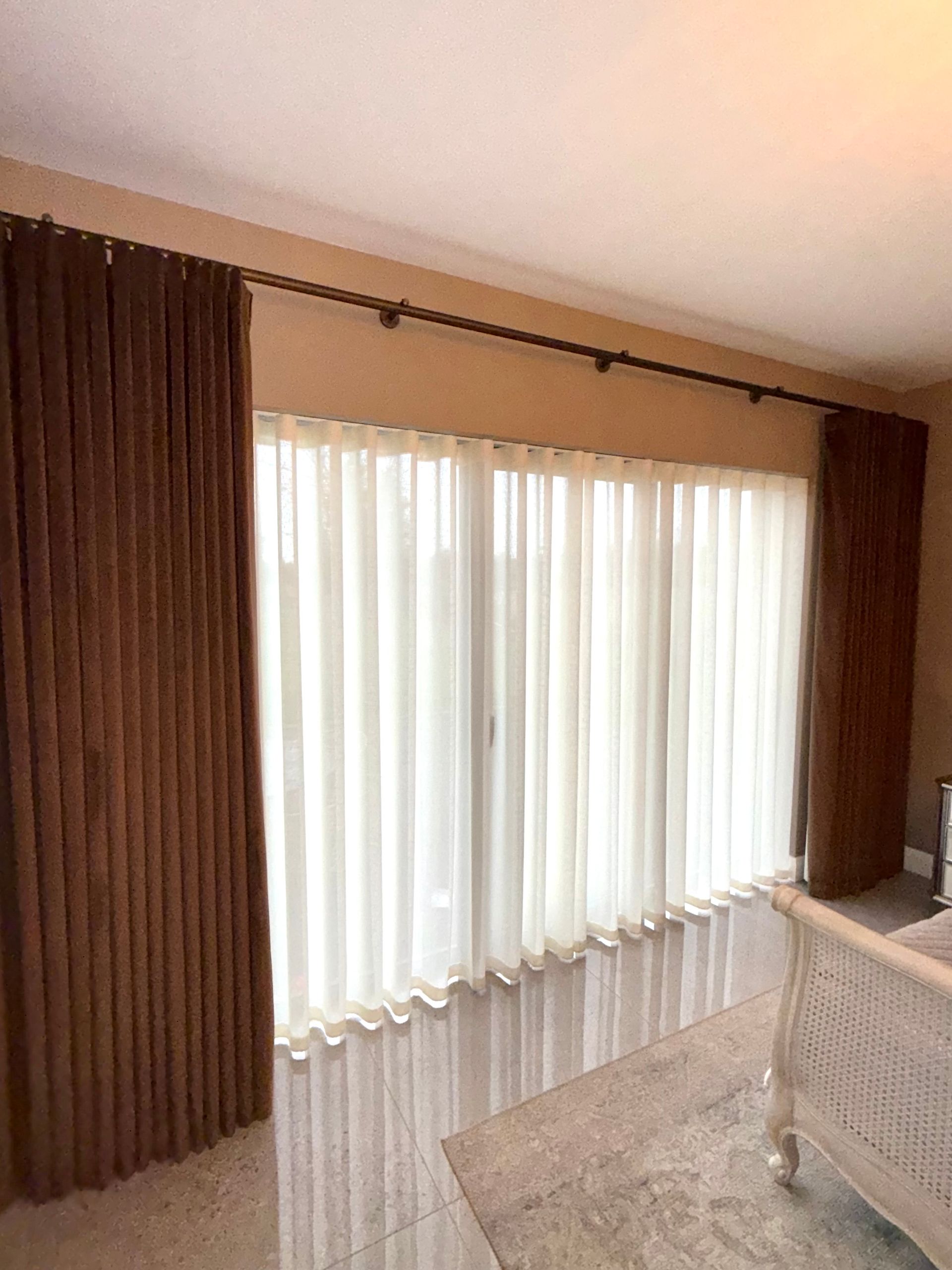 Brown and sheer curtains hang over a window. Beige walls and a rug are visible.
