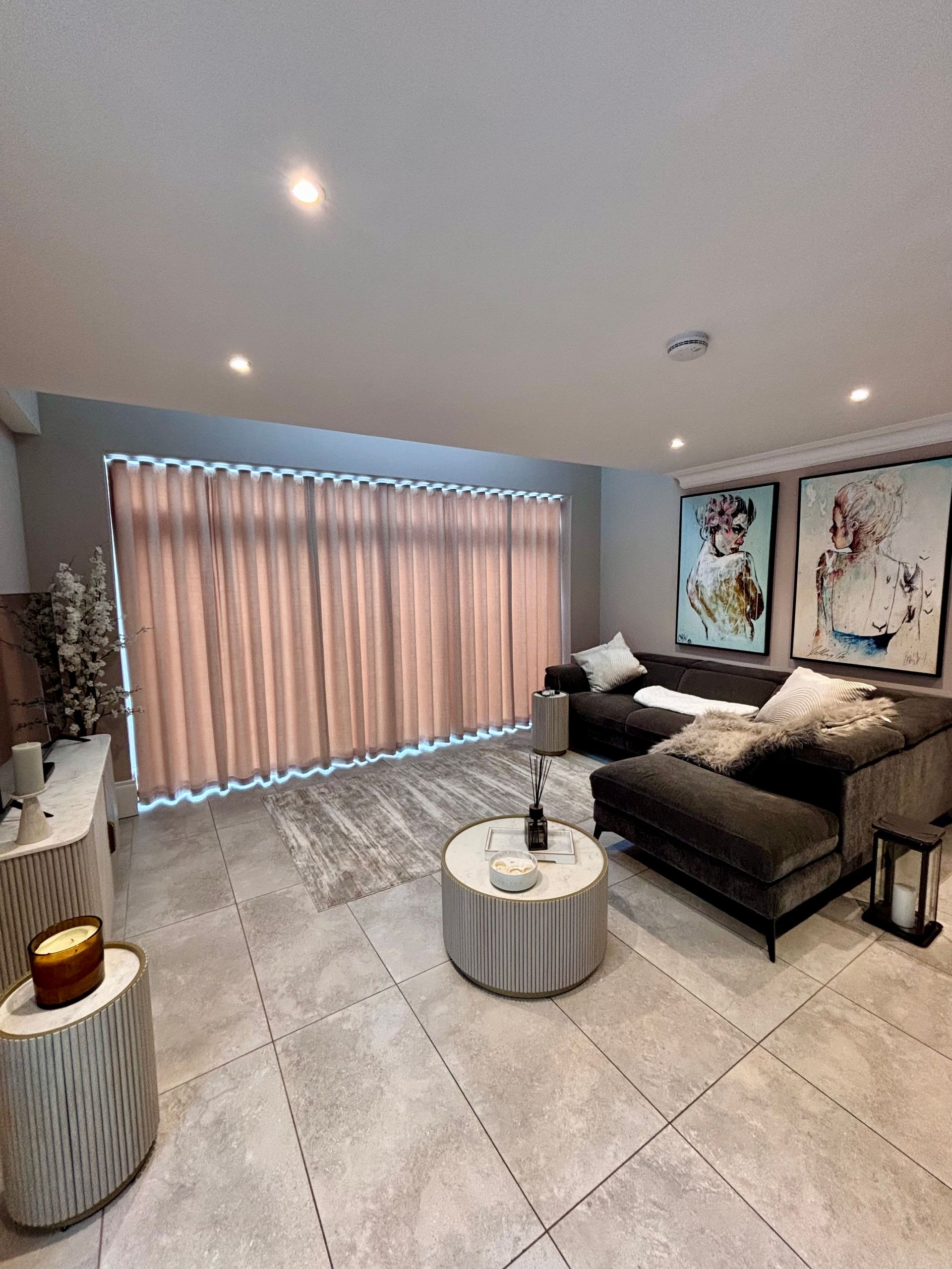 Living room with gray sofa, patterned rug, marble coffee table, artwork, and curtains.