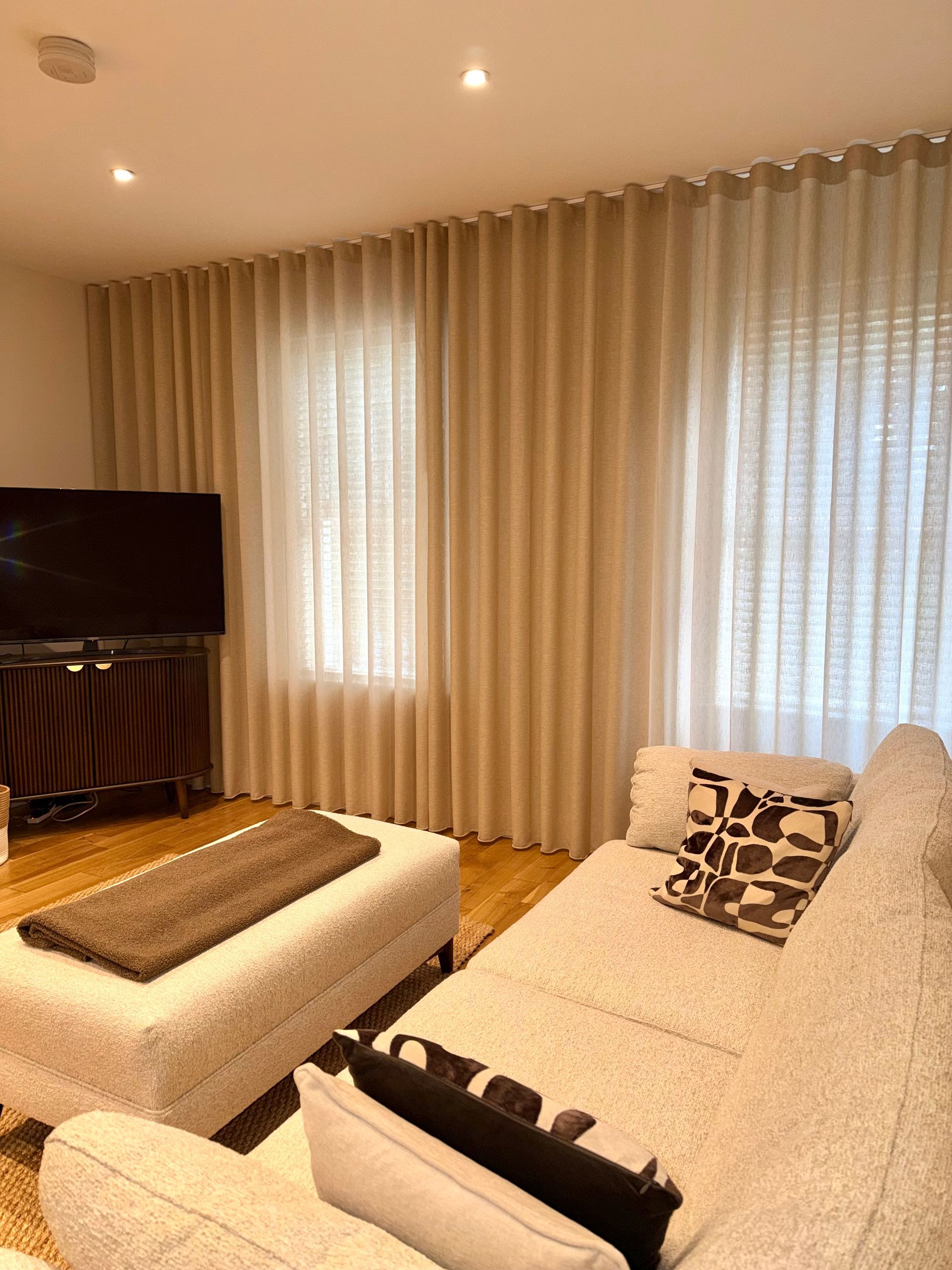 Living room with beige curtains, a white sofa, and a television.