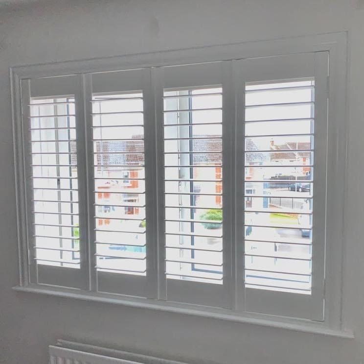 A window with shutters on it and a view of a city.