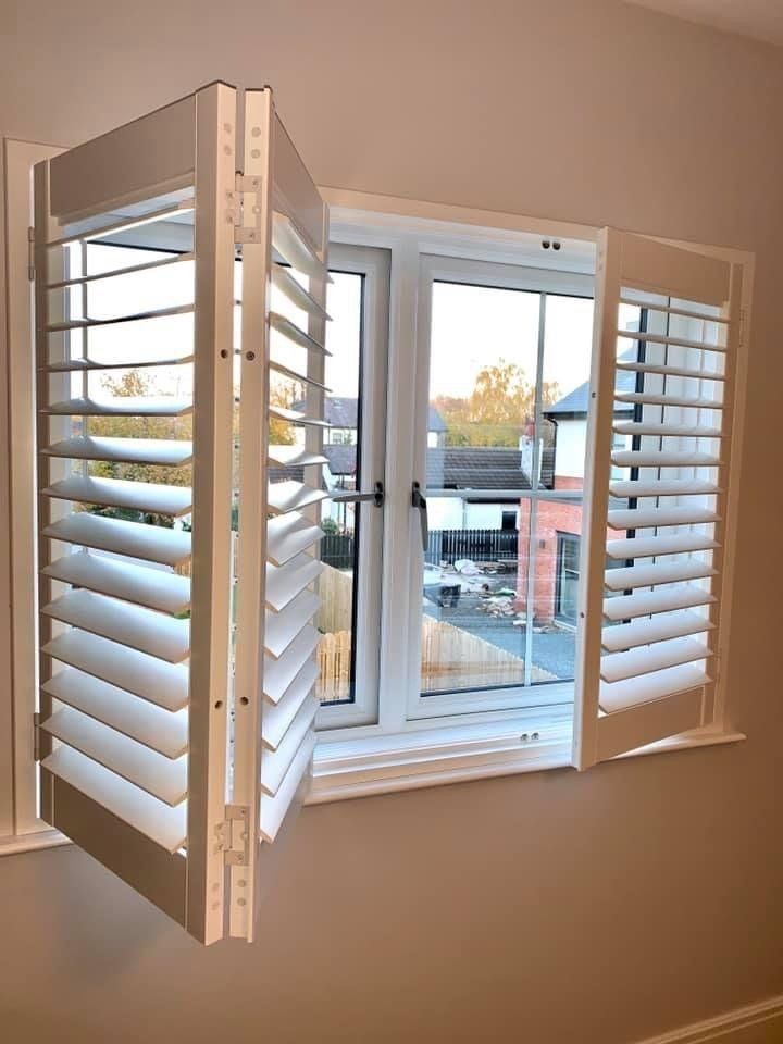 A window with shutters open and a view of a house