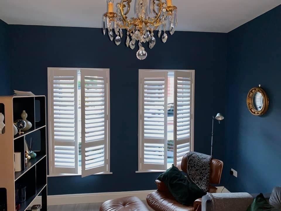A living room with blue walls and white shutters