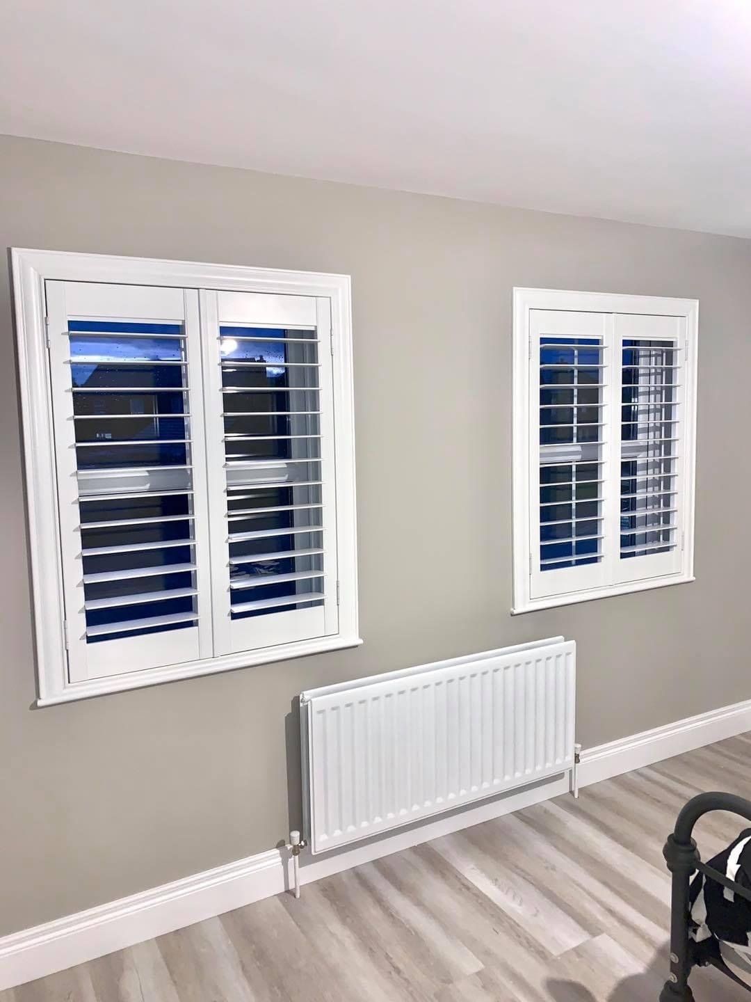 A bedroom with two windows and a radiator.