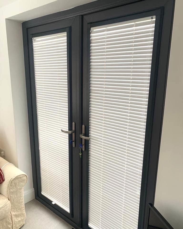 A pair of french doors with blinds on them in a living room.