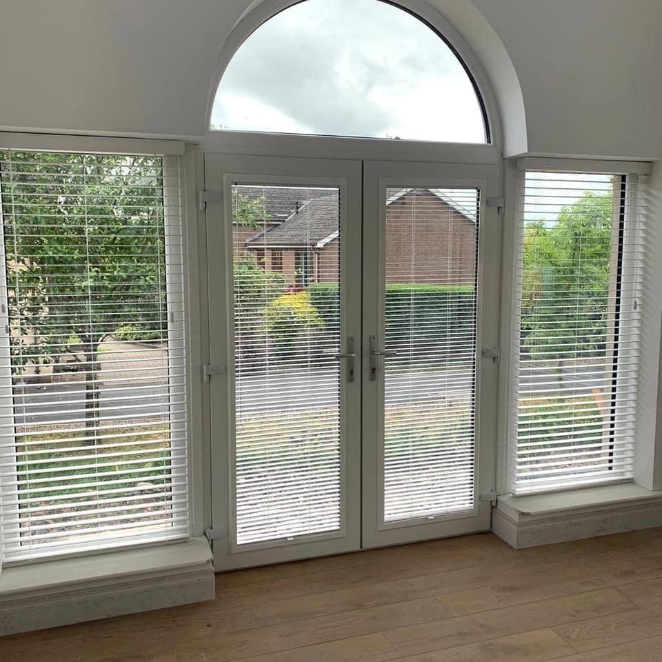 A living room with a large window and blinds on the windows.