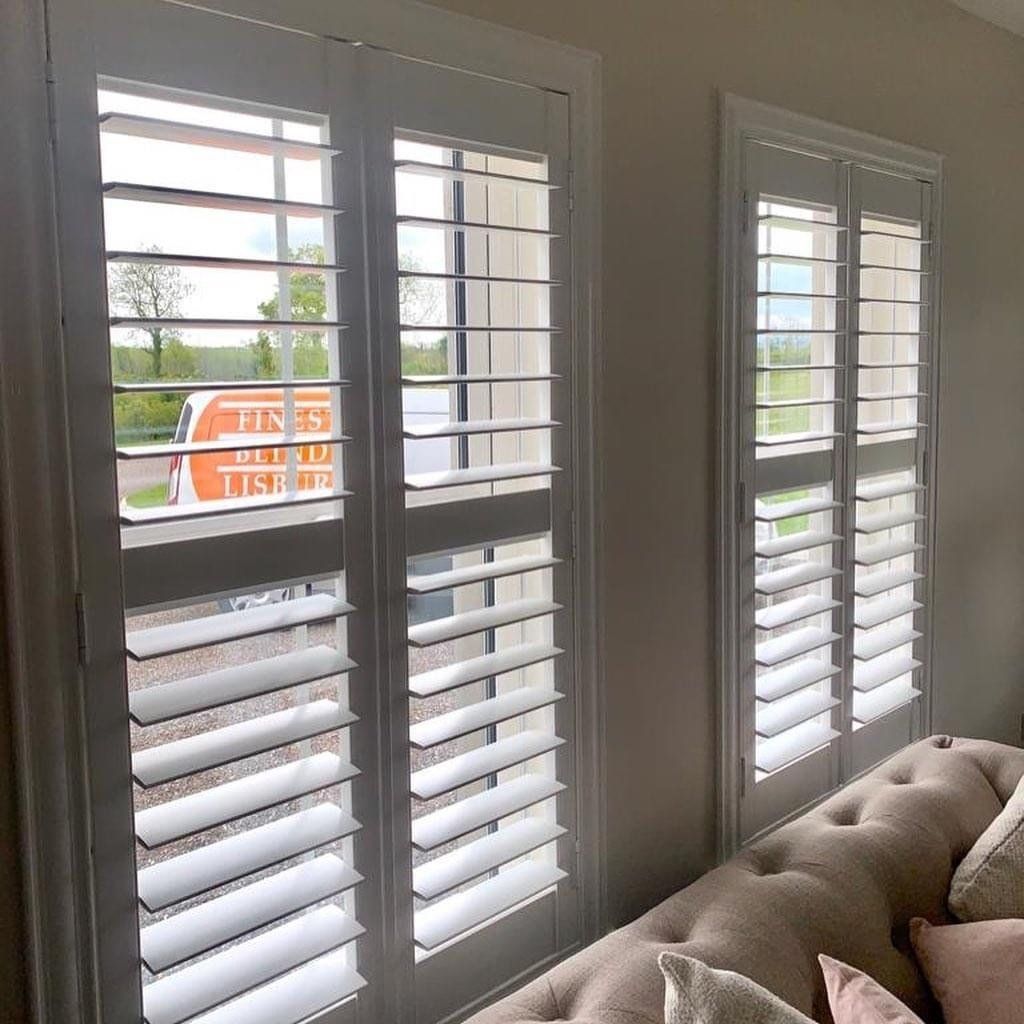 A living room with a couch and shutters on the windows.