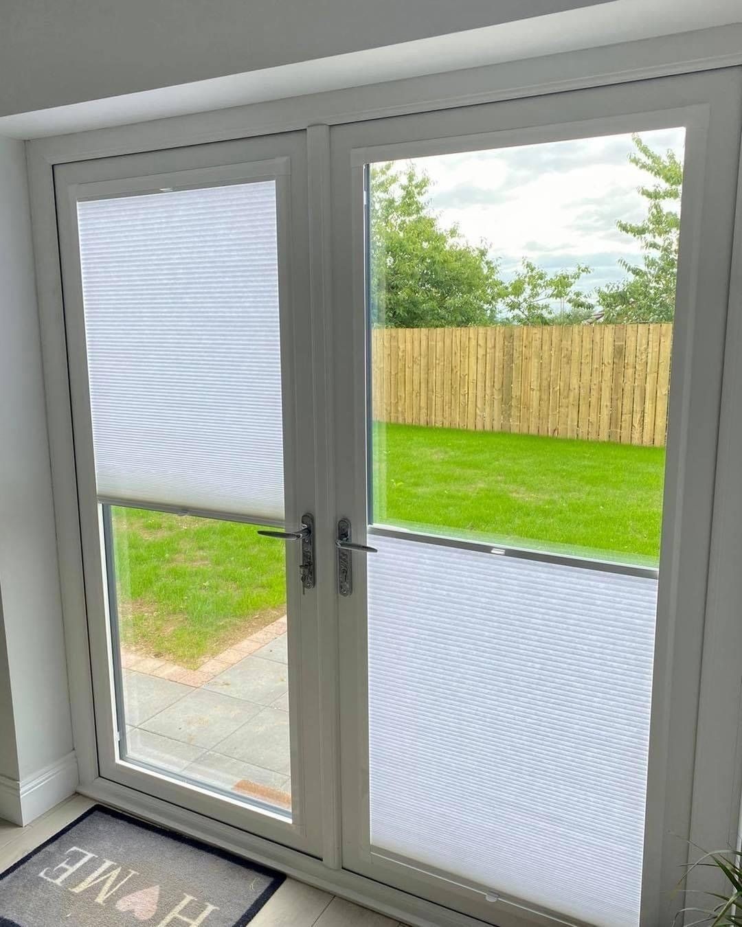 A sliding glass door with blinds on it and a rug on the floor.