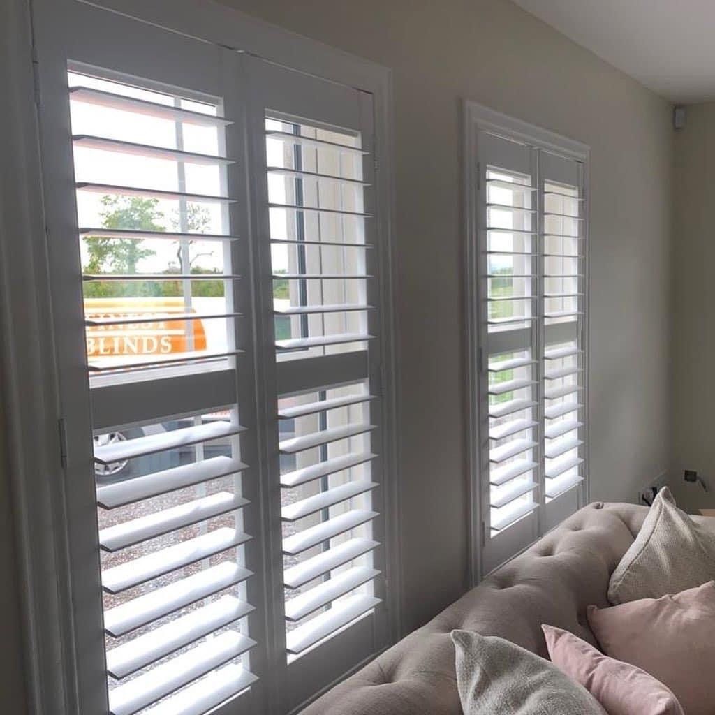 A living room with a couch and shutters on the windows.