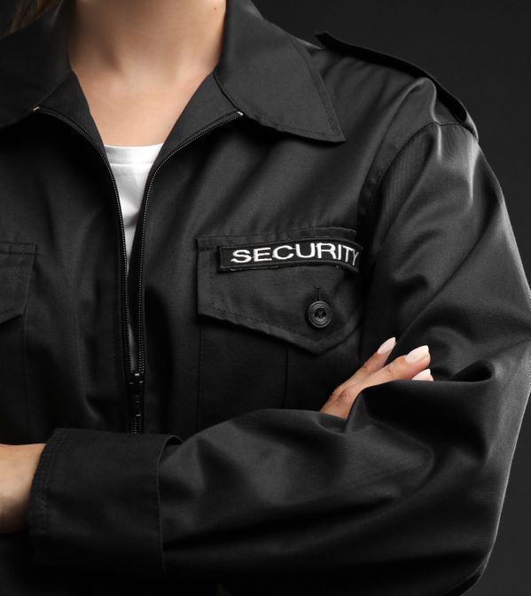 A Woman Wearing A Black Security Jacket With Her Arms Crossed — Coastal Protection Services Pty Ltd In Woy Woy, NSW