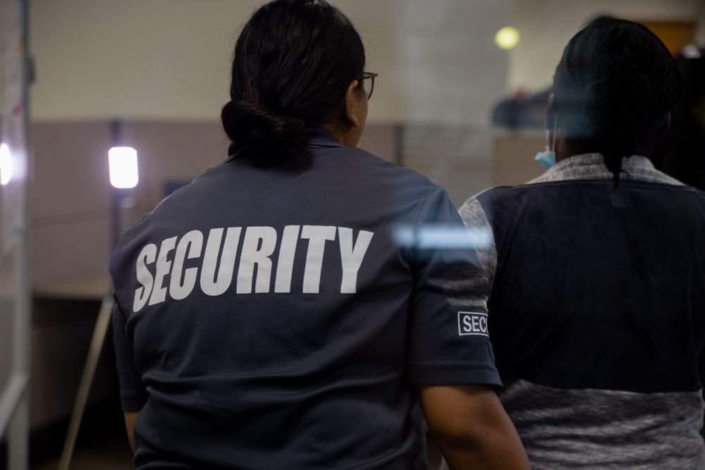 A Woman Wearing A Security Shirt Is Standing Next To Another Woman— Coastal Protection Services Pty Ltd In Newcastle, NSW