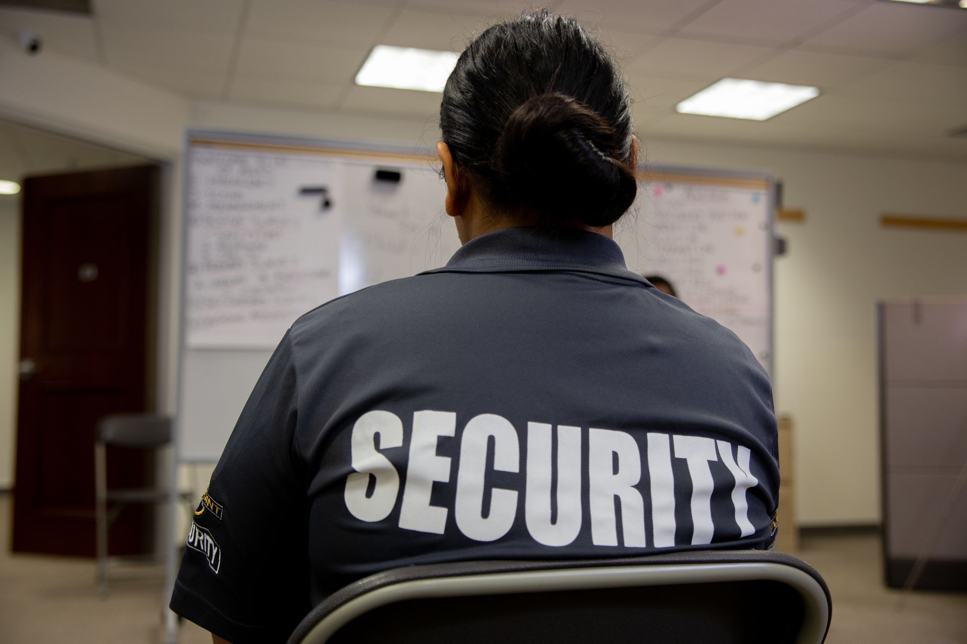 A Woman In A Security Uniform Is Sitting In A Chair — Coastal Protection Services Pty Ltd In Newcastle, NSW