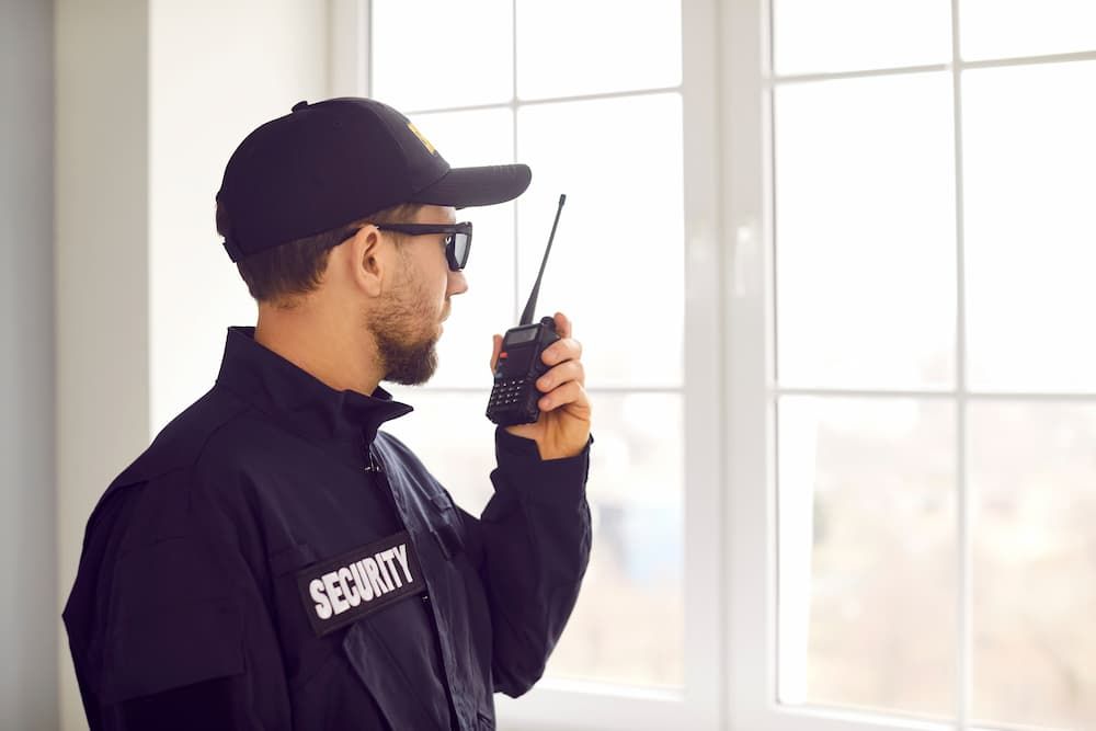 A Security Guard Is Talking On A Walkie Talkie — Coastal Protection Services Pty Ltd In Bateau Bay, NSW
