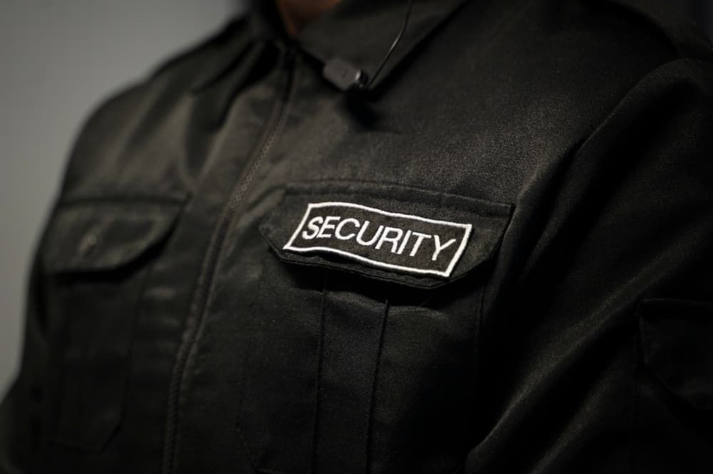 A Security Guard Wearing Black Jacket Has A Security Patch On His Chest — Coastal Protection Services Pty Ltd In Narara, NSW