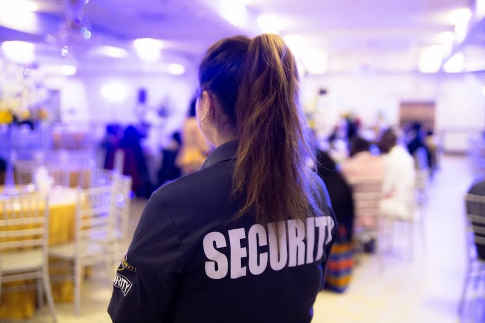 A Security Guard Is Standing In Front Of A Crowd Of People In A Room — Coastal Protection Services Pty Ltd In Terrigal, NSW