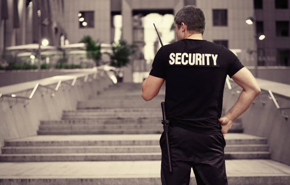 A Security Guard Is Standing In Front Of A Set Of Stairs — Coastal Protection Services Pty Ltd In Berkeley Vale, NSW