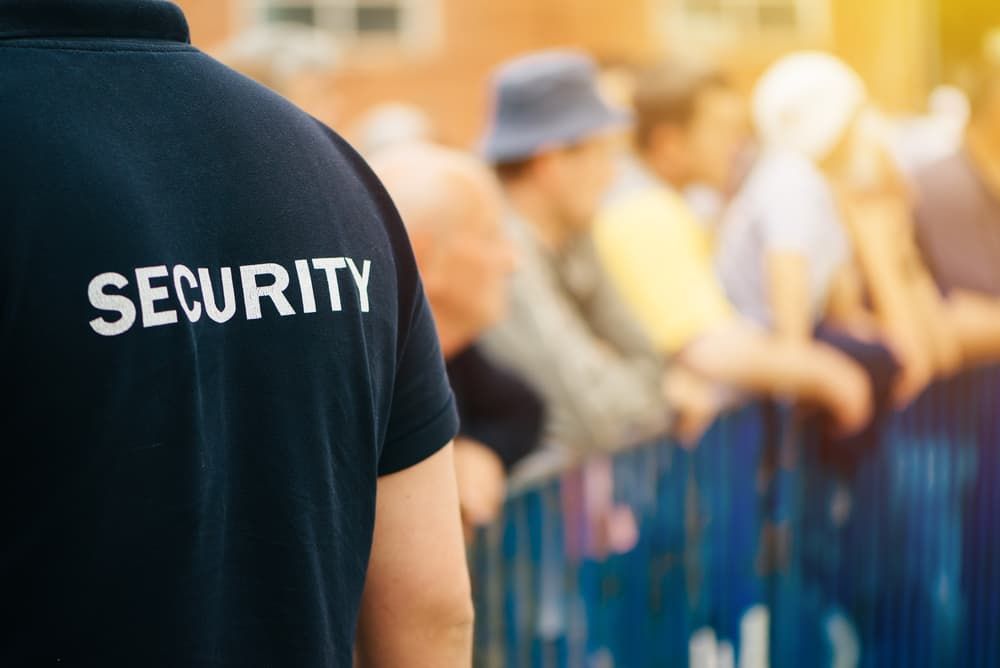A Security Guard Is Standing In Front Of A Crowd Of People — Coastal Protection Services Pty Ltd In Narara, NSW