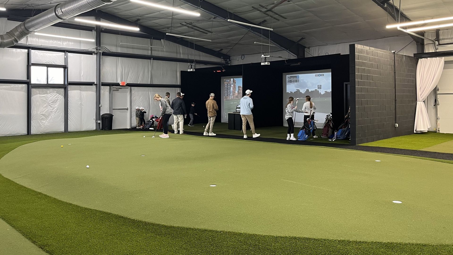 a group of people are playing golf in an indoor golf simulator .