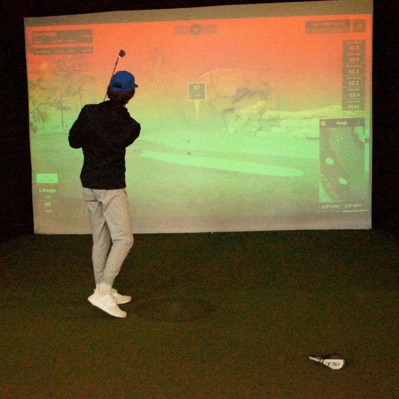 a man is swinging a golf club playing a round on a golf simulator