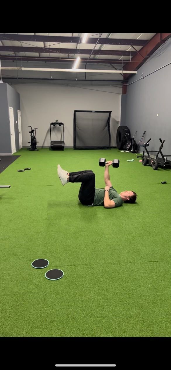 a person is laying on the floor with a dumbbell in a gym .