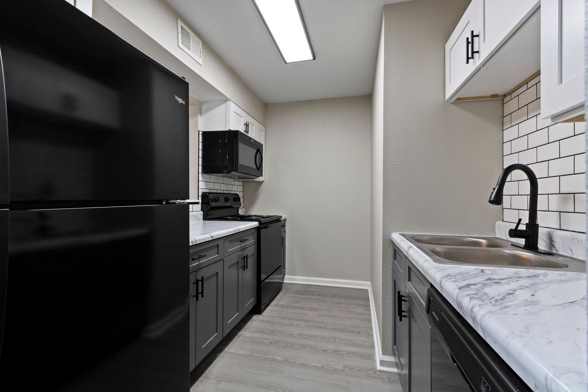 Modern kitchen with black appliances, gray cabinets, white countertops, and a subway tile backsplash.