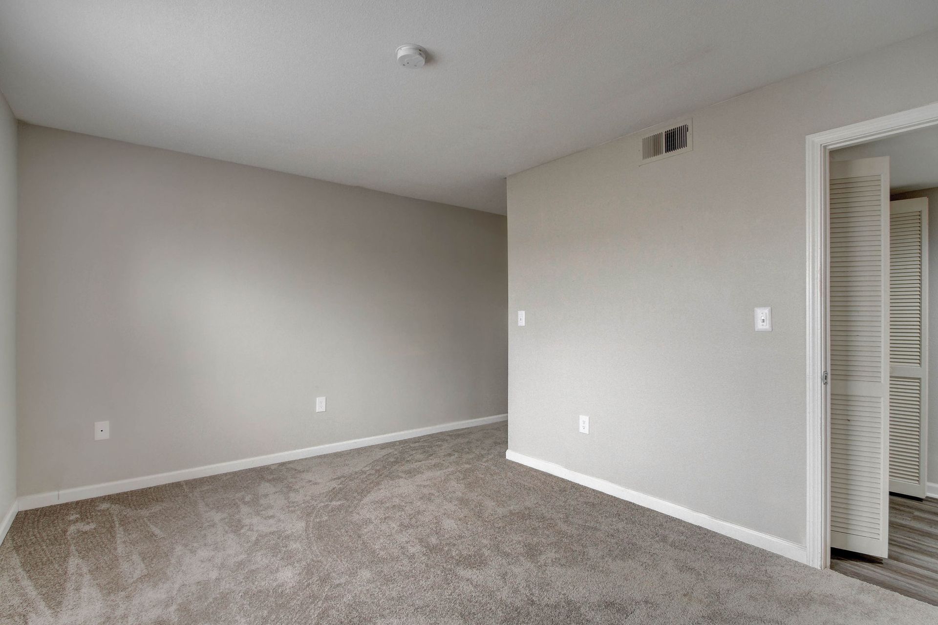 Empty room with gray walls, carpet, and a door.
