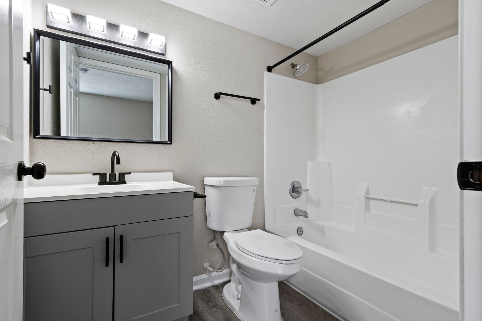 Gray bathroom with a vanity, toilet, and tub/shower combo.
