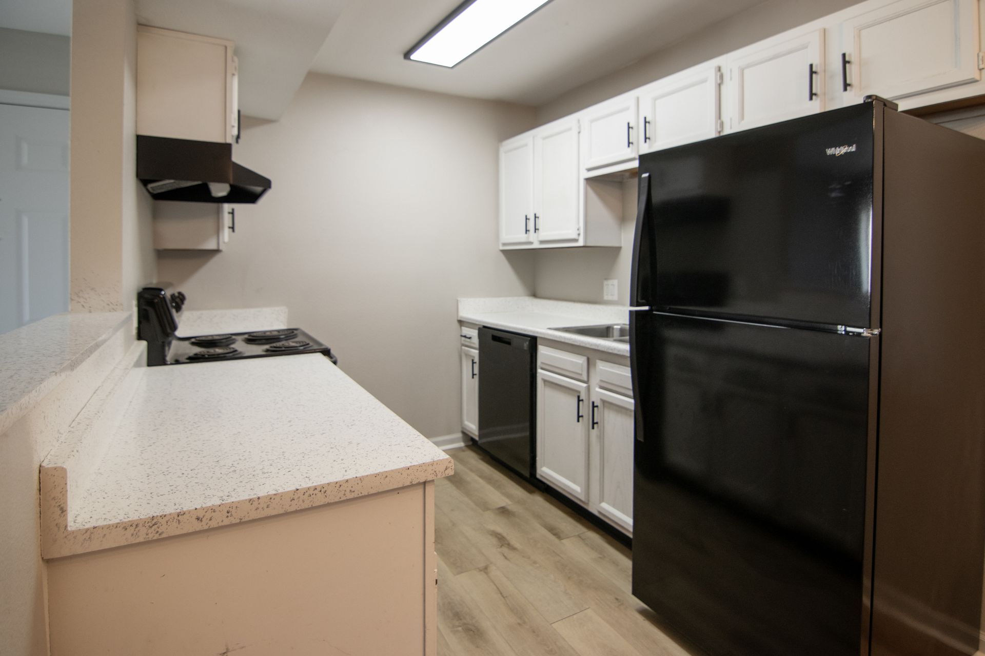 Kitchen with white cabinets, black appliances, and light countertops.