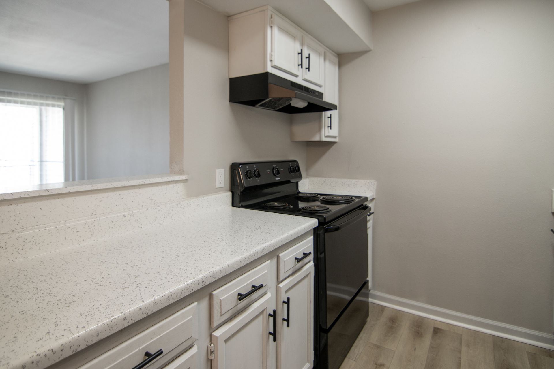 Kitchen with white cabinets, black stove, and light gray walls.