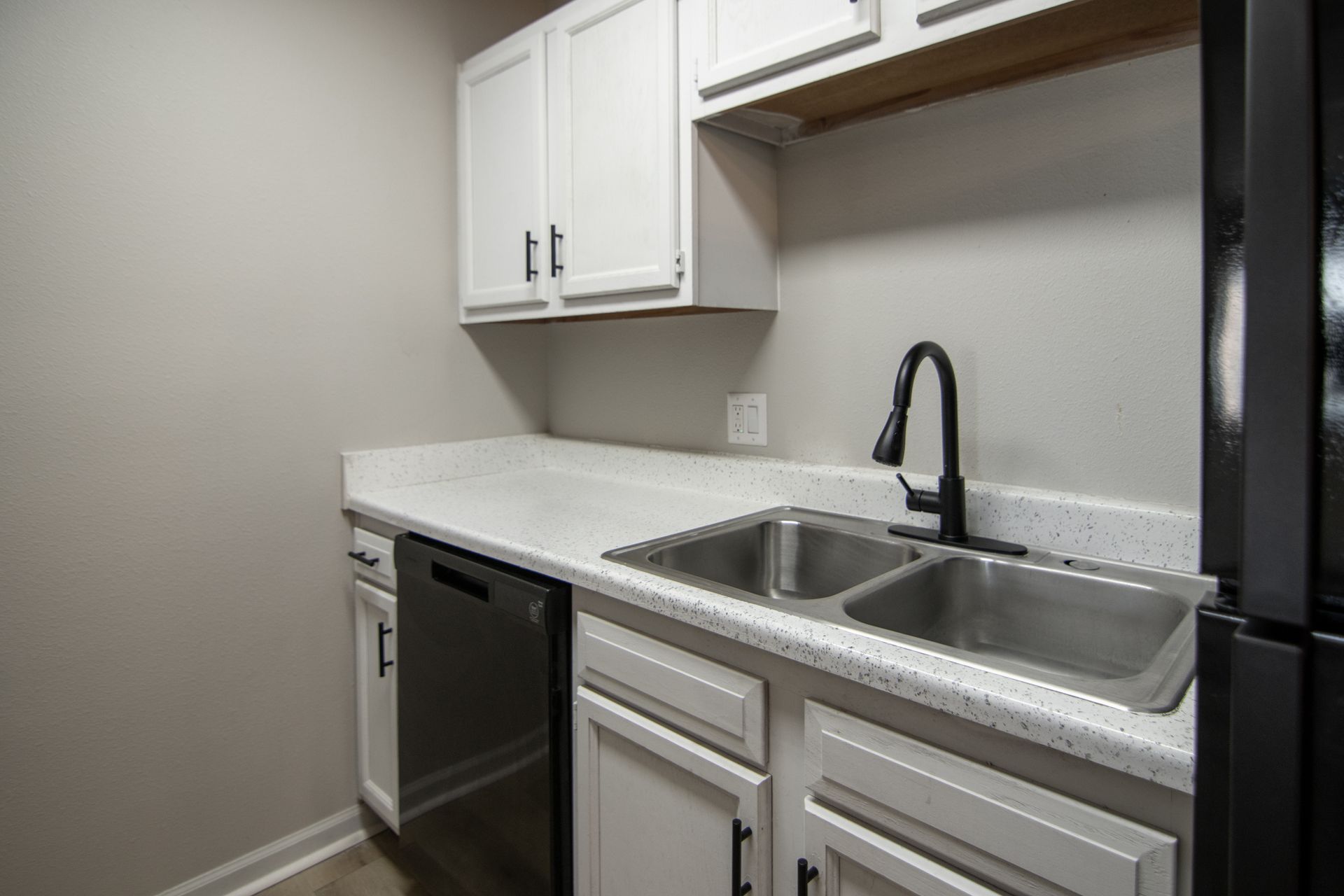 White kitchen cabinets, stainless steel sink, and black faucet.