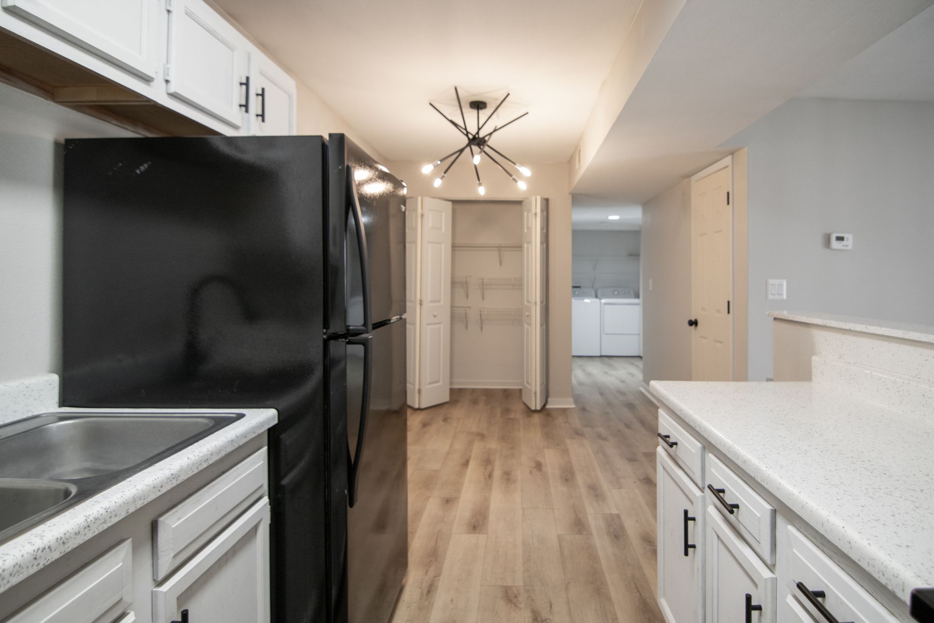 Modern kitchen with white cabinets, black appliances, and wood flooring.