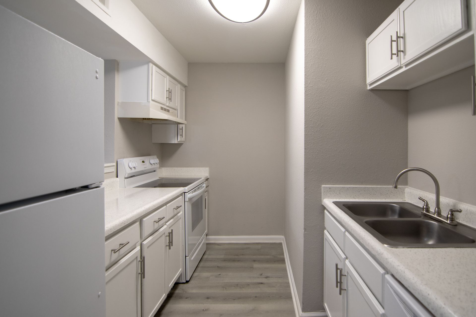 White kitchen with appliances and cabinets; light gray walls and flooring.