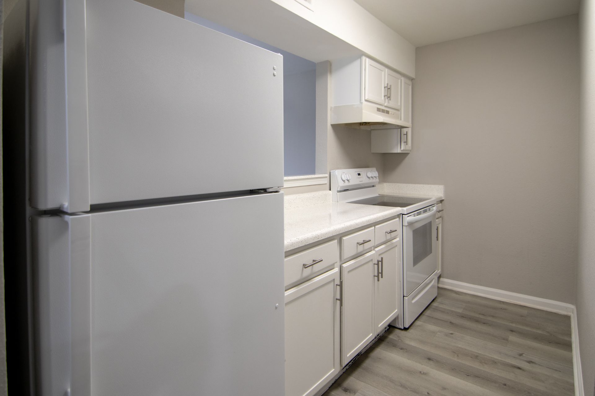 White kitchen with a refrigerator, cabinets, stove, and microwave.