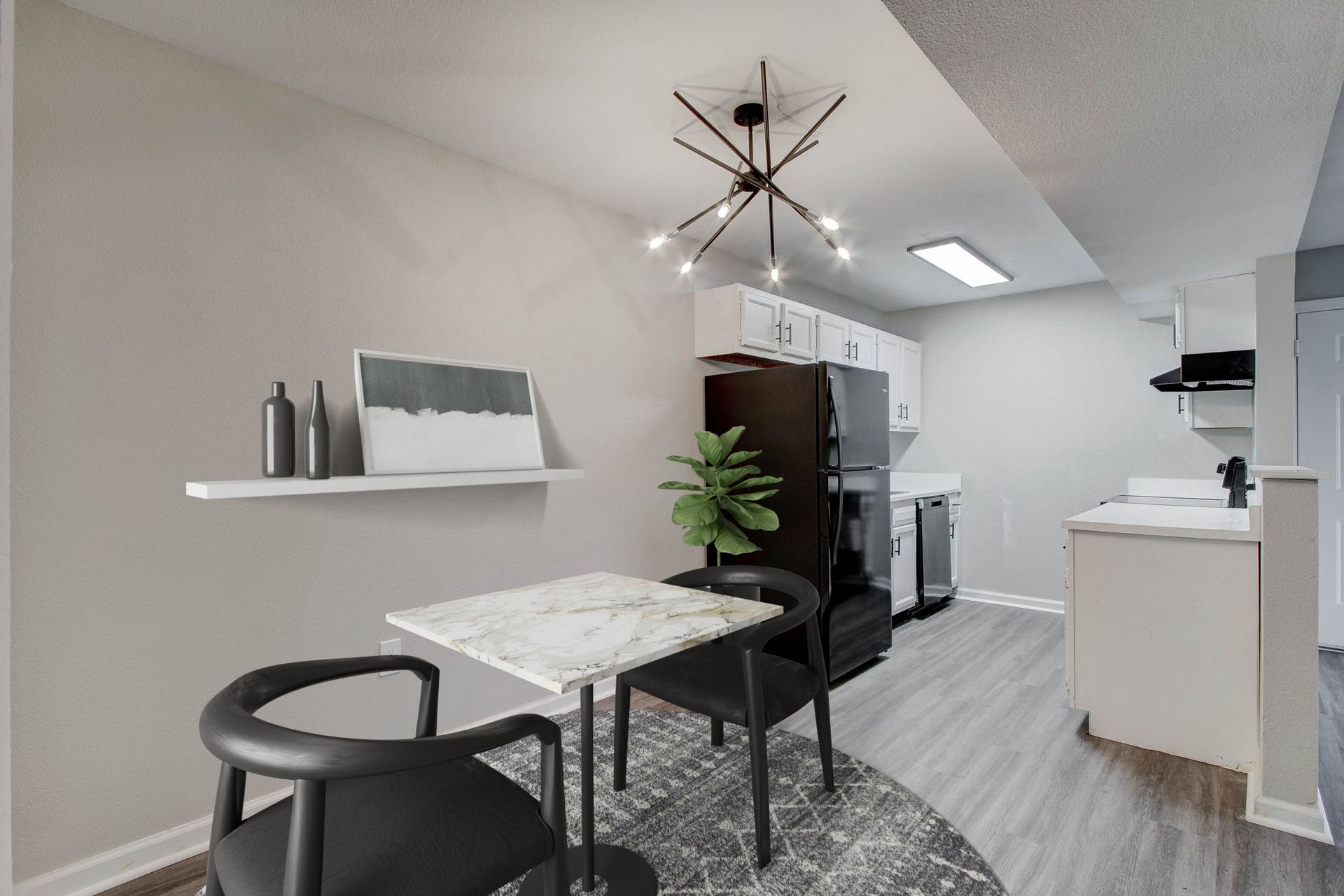 A dining area with a table, two chairs, and a kitchen with black appliances.
