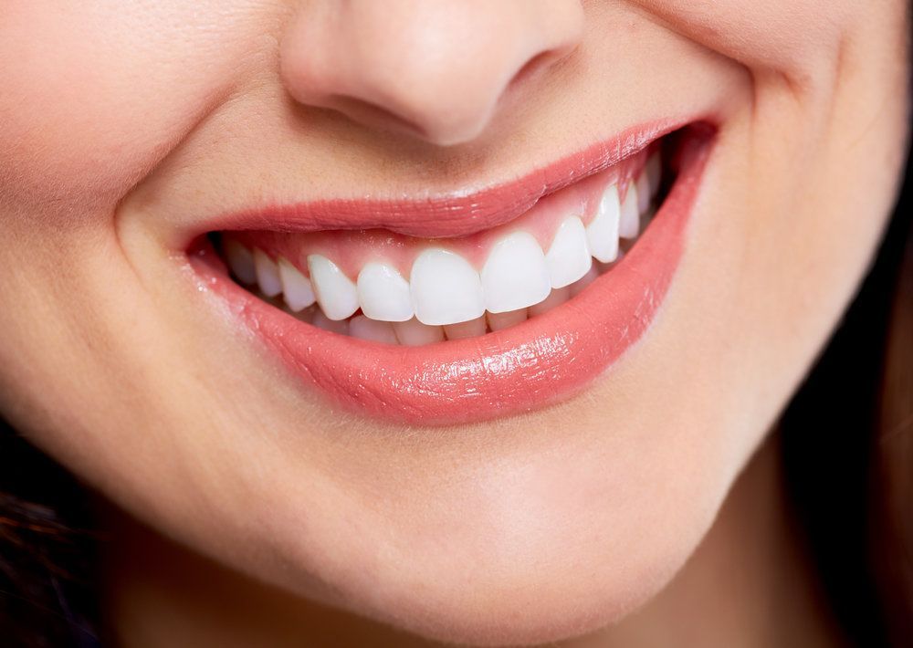 A close up of a woman 's smile with white teeth and pink lips.